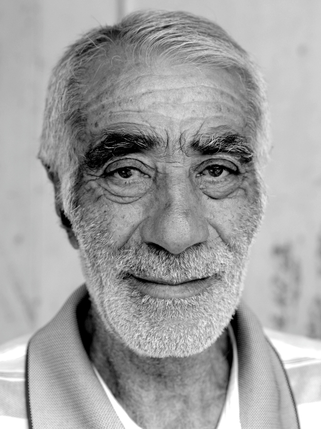 Portrait eines sympathischem, älteren Mannes, der verhalten in die Kamera lächelt