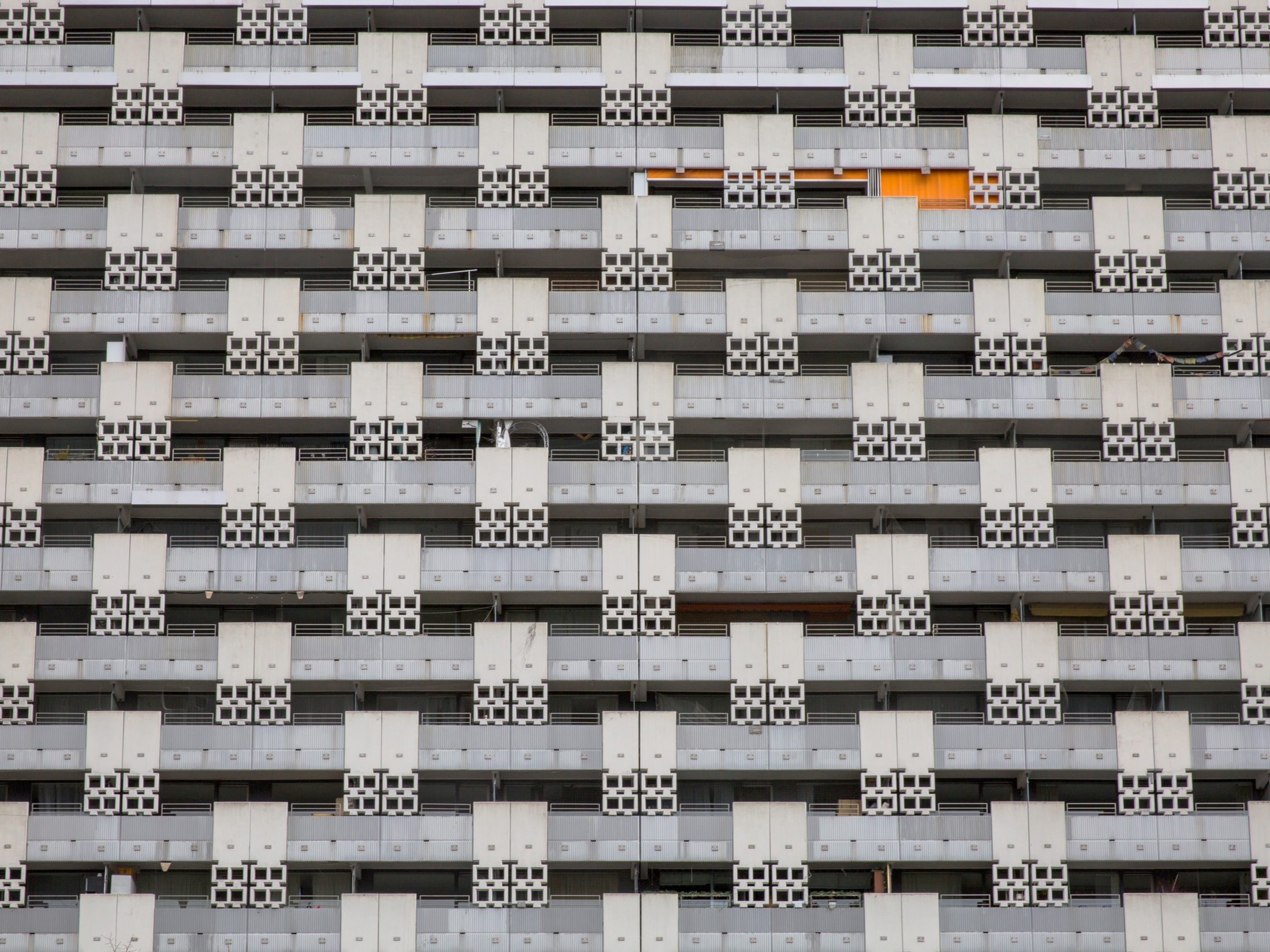 Beton-Häuserfassade mit einem orangenen Vorhang vor einer der Wohnungen