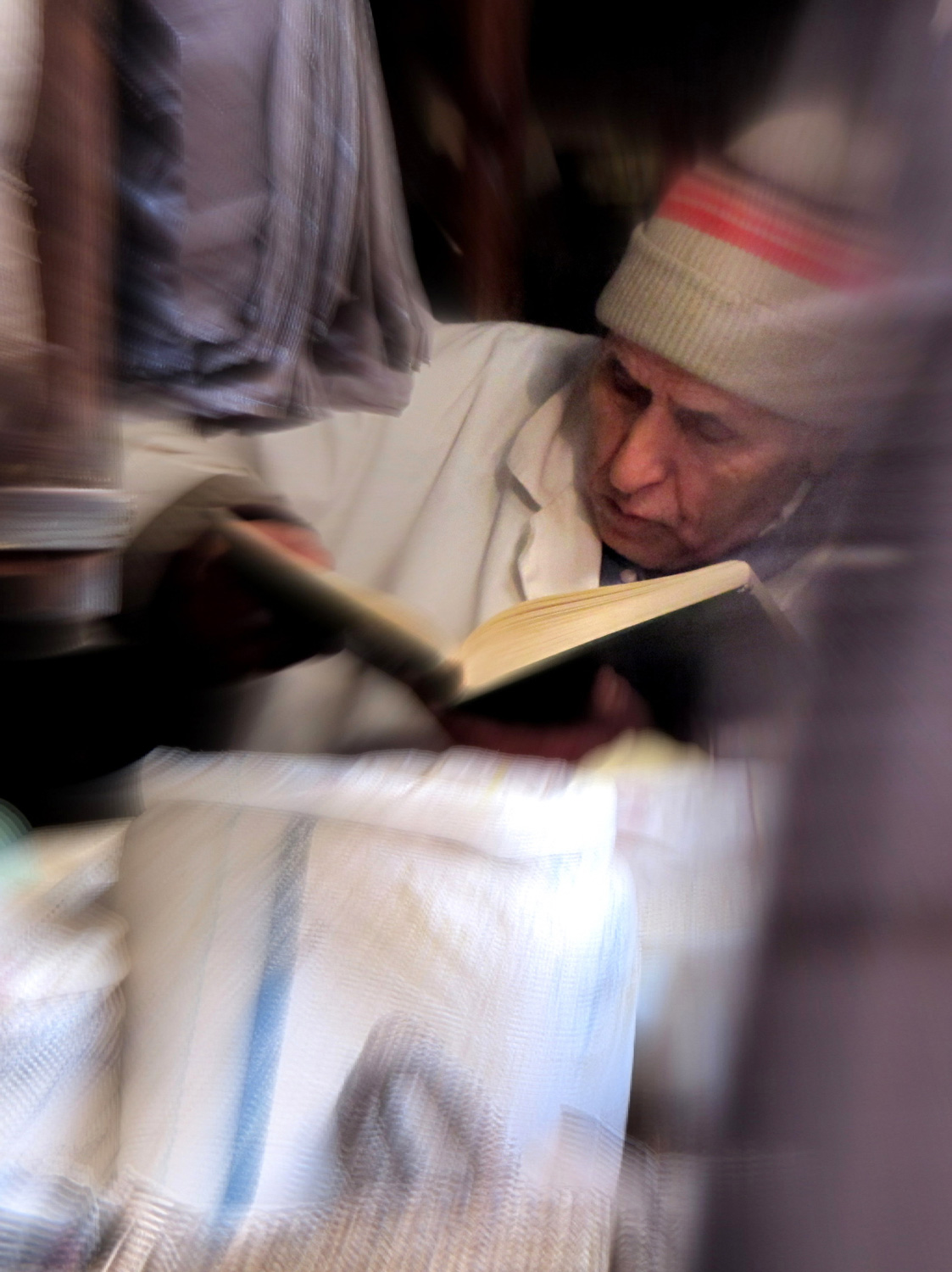 ein älterer Mann mit Mütze liest ein Buch