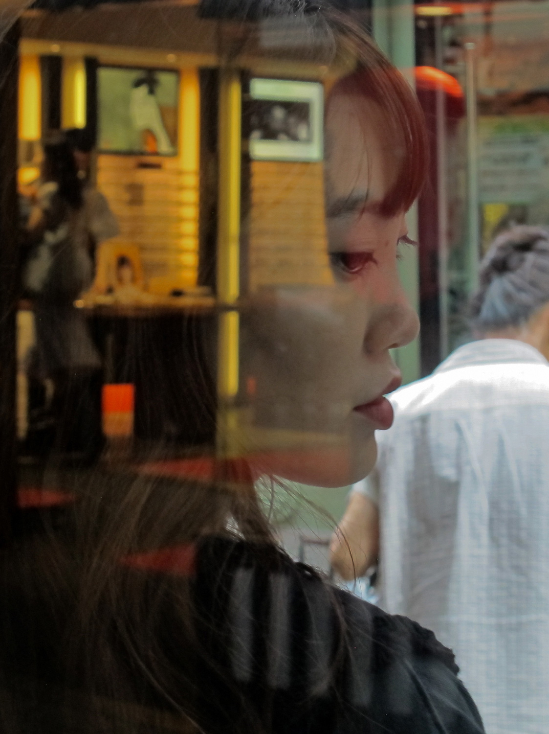 eine junge Frau im Profil hinter einer Glasscheibe